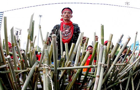Tailândia - 9h32 - Manifestante se posiciona atrás de uma barricada feita de bambus, no distrito comercial de Silom. Os "camisas vermelhas" desistiram de um protesto no bairro de negócios de Bangcoc